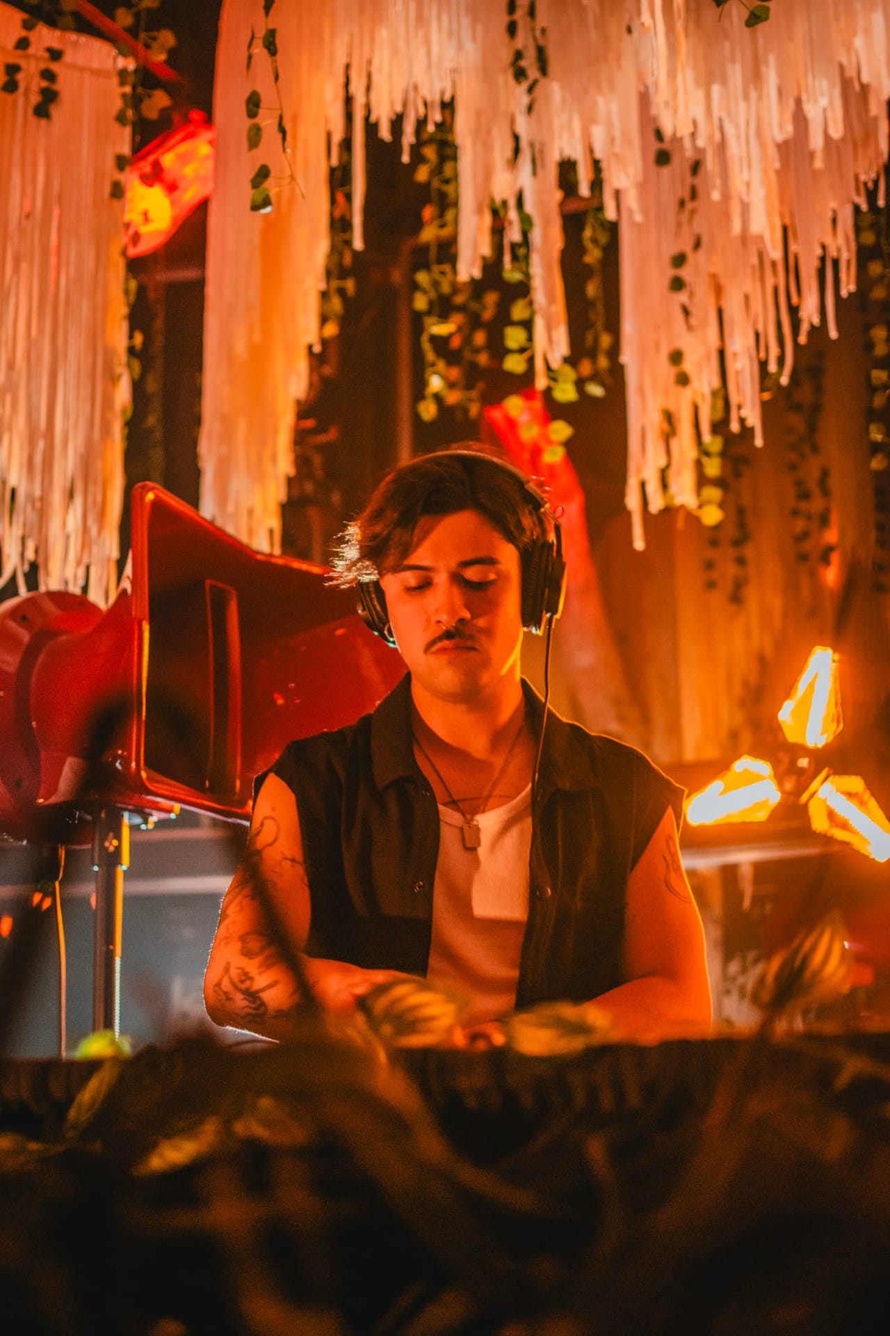DESIGG head down over the mixer at El Ático Club, under the fringe curtain and its glowing lamps